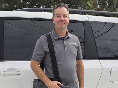 A man posing for a photo with his workbag next too a car